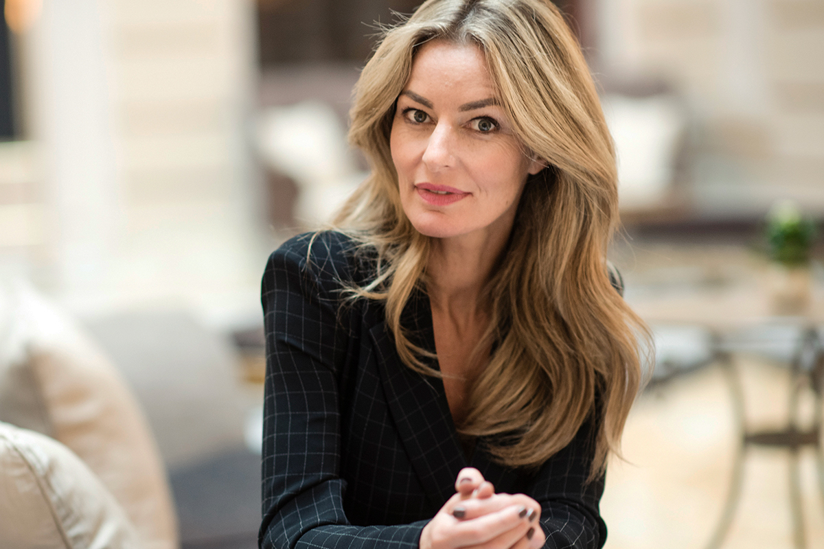 a woman looking at the camera while sitting on the couch after seeing the best facelift surgeon in NYC