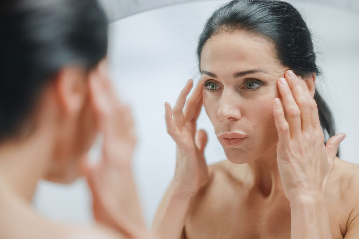 older woman looking in the mirror and considering a revision facelift in NYC