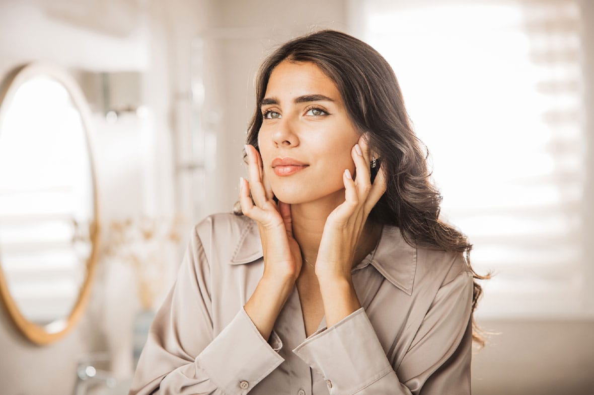 woman looking in the mirror while recovering from her mini facelift in NYC