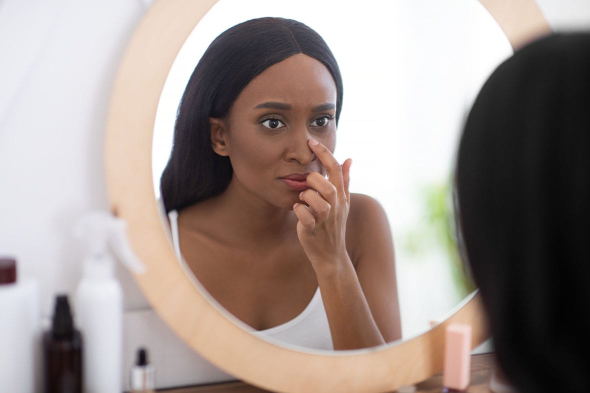 woman looking in the mirror during her rhinoplasty recovery in NYC
