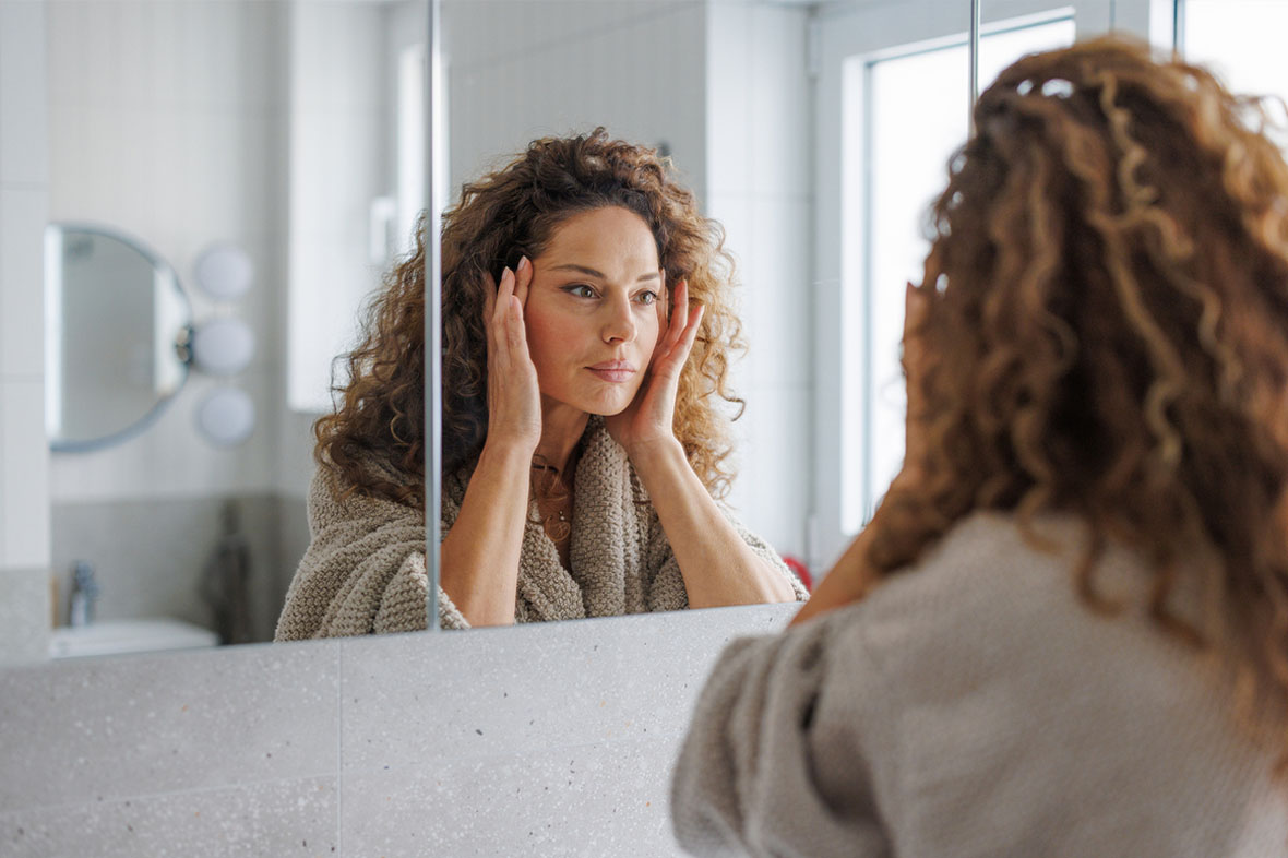 woman looking in the mirror before her facelift in NYC